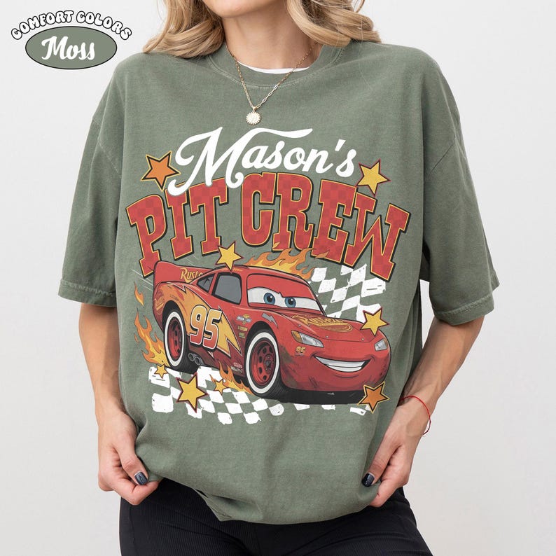 May include: An olive green t-shirt with a graphic of a red race car with the number 95 and the text "Mason's PIT CREW". The shirt also features the text "Comfort Colors" and "Moss".