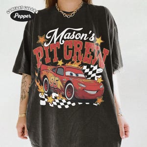 May include: Black t-shirt with a graphic of Lightning McQueen from the movie Cars, flames, and the text "Mason's Pit Crew." The shirt also features the Comfort Colors and Pepper logos.