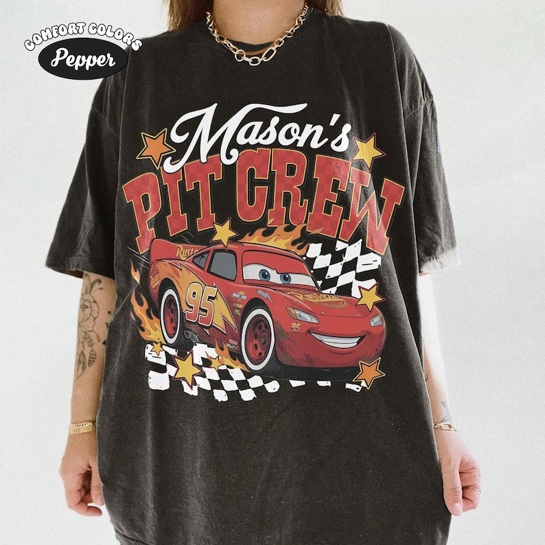 May include: Black t-shirt with a graphic of Lightning McQueen from the movie Cars, flames, and the text "Mason's Pit Crew." The shirt also features the Comfort Colors and Pepper logos.