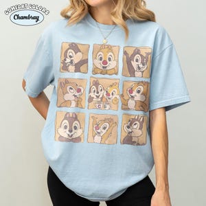 May include: Pale blue t-shirt with a grid of nine cartoon chipmunks in different poses. The shirt has the words "Comfort Colors" and "Chambray" printed on it. The chipmunks are in brown squares.
