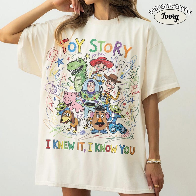 Puede incluir: Una camiseta de color marfil con un gr&aacute;fico colorido de los personajes de Toy Story, incluyendo a Woody, Buzz Lightyear, Rex y el Sr. Patata. El dise&ntilde;o incluye l&iacute;neas estilo garabato, estrellas y el texto "TOY STORY" e "I KNEW IT, I KNOW YOU."
