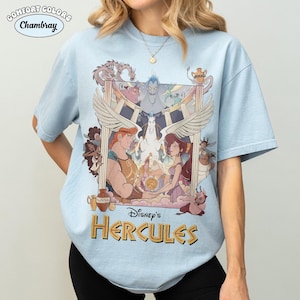 May include: Light blue Comfort Colors Chambray t-shirt featuring a graphic from Disney's Hercules. The design includes Hercules, Megara, Pegasus, Hades, and other characters. The text "Disney's Hercules" is in gold lettering.