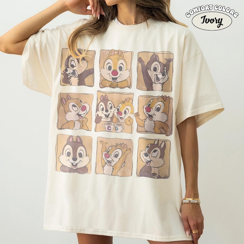 May include: Ivory-coloured t-shirt with a grid of nine cartoon chipmunks in different poses. The shirt has a relaxed fit and short sleeves. The text "COMFORT COLORS" and "Ivory" are printed on the upper right corner.