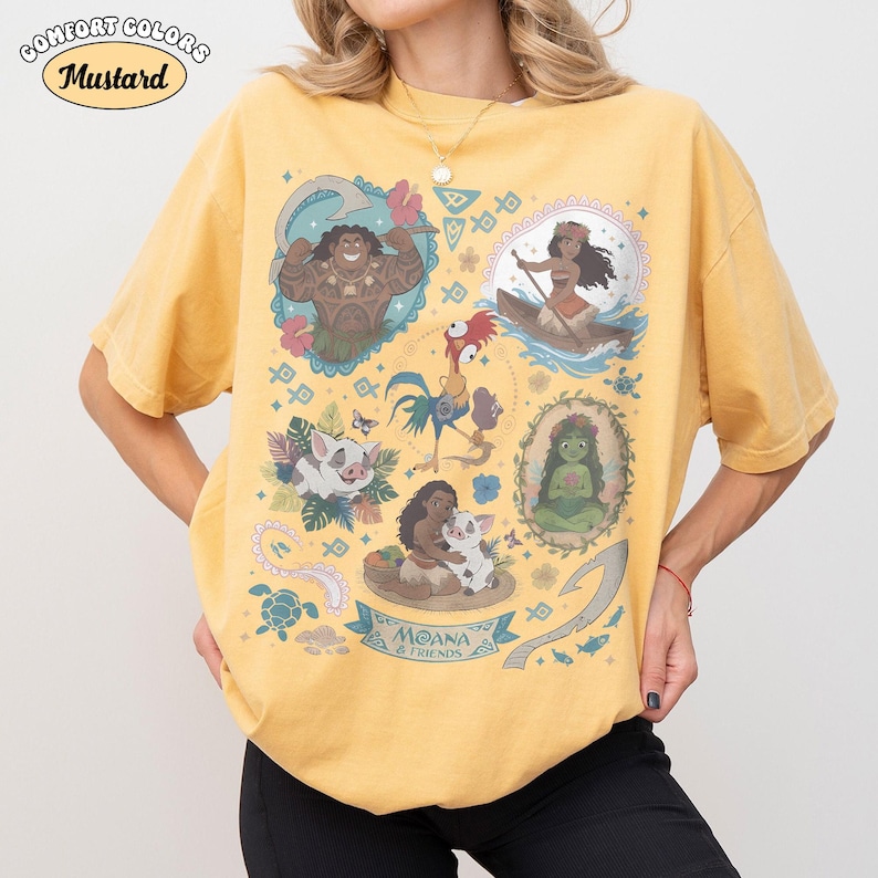 May include: Mustard-colored Comfort Colors t-shirt featuring colorful illustrations of characters from the animated film Moana. The shirt includes the text "MOANA & FRIENDS" and various character portraits.