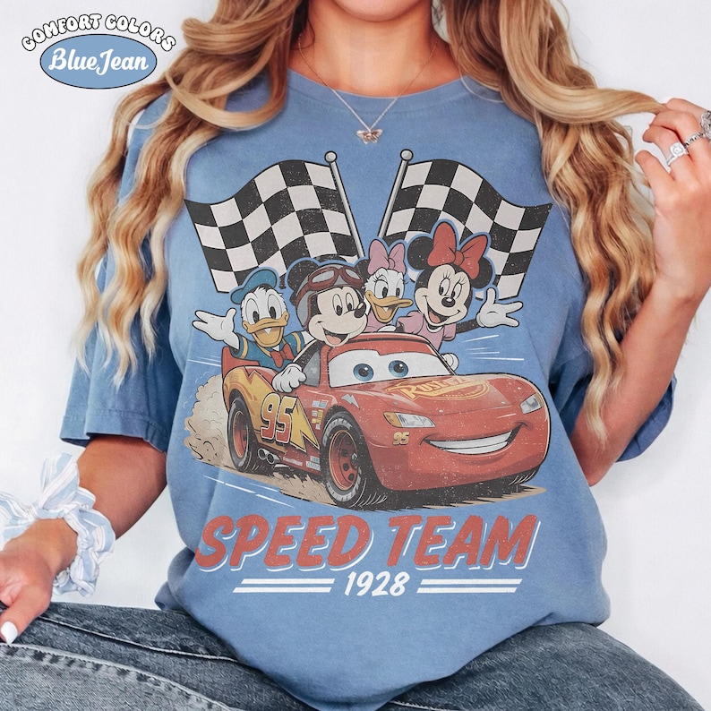 May include: Blue Comfort Colors t-shirt with a graphic of Disney characters Mickey Mouse, Donald Duck, Daisy Duck, and Minnie Mouse in a race car with checkered flags. The text "SPEED TEAM 1928" is printed below the car.