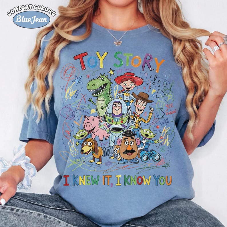 Puede incluir: Una camiseta azul de manga corta con un gr&aacute;fico colorido de los personajes de Toy Story, incluyendo a Woody, Buzz Lightyear, Jessie, Rex, Hamm, Slinky Dog, Mr. Potato Head y Aliens, con el texto TOY STORY e I KNEW IT, I KNOW YOU.