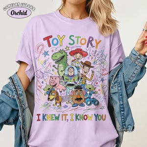 Puede incluir: Una camiseta de color morado claro con un gr&aacute;fico colorido de los personajes de Toy Story, incluyendo a Woody, Buzz Lightyear, Jessie, Rex, Hamm, Slinky Dog, Mr. Potato Head y alien&iacute;genas. El texto dice TOY STORY e I KNEW IT, I KNOW YOU.