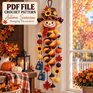 May include: A crochet hanging decoration featuring a scarecrow with a brown hat, a red scarf, and a spiral body. The piece includes dangling elements like sunflowers, pumpkins, acorns, maple leaves, and blue overalls. Text reads PDF FILE CROCHET PATTERN Autumn Scarecrow Hanging Decoration.