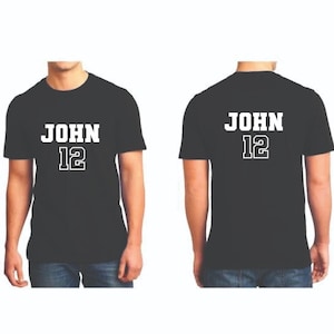 May include: Black t-shirts with the name "JOHN" and the number "12" printed in white. The front and back of the shirts are displayed. The text is in a bold, blocky font.