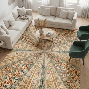 May include: An overhead shot of a living room featuring a large, patterned area rug with a sunburst design in beige, brown, and blue. Two beige sofas, two green armchairs, and a round wooden coffee table complete the room's decor.