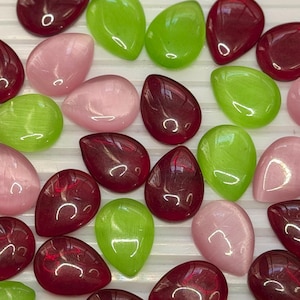 May include: An assortment of teardrop-shaped cabochons in various colors. The cabochons are in shades of pink, green, and burgundy. The polished stones have a smooth, glossy finish and are arranged closely together.