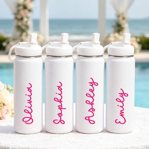 May include: Four white cylindrical water bottles with white lids and flip-up spouts. Each bottle features a unique name printed vertically in a bright pink cursive font. The names displayed on the bottles are Olivia, Sophia, Ashley, and Emily.