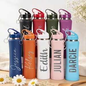 Könnte beinhalten: Ein Set aus drei Keramikbechern mit gesprenkelter, matter Oberfläche. Die Becher sind in Creme-, Hellgrau- und Dunkelgrautönen gehalten. Jeder Becher hat ein schlichtes, minimalistisches Design und einen abgerundeten Griff.