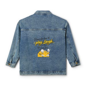 Könnte beinhalten: Eine blaue Jeansjacke mit einem Rückendruck, der den Text "Remember how to play, Laugh, and lose track of time" zeigt. Das Design enthält zwei gelb-weiße Strichmännchen, die über einer gelben, halbkreisförmigen Zifferblattgrafik platziert sind.