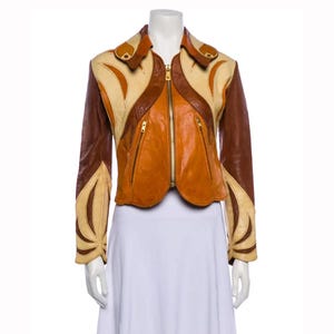 May include: A vintage leather jacket in a patchwork design. The jacket features a color palette of brown, tan, and orange, with a full-length zipper and two front pockets. The jacket has a unique, retro aesthetic.