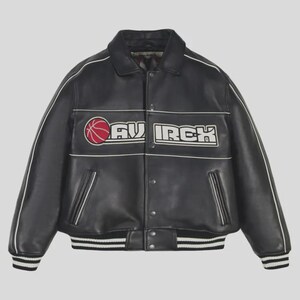 Puede incluir: Chaqueta de cuero negro con ribetes blancos y un logotipo de baloncesto. La chaqueta presenta la palabra "AVURCH" en letras blancas con un gr&aacute;fico de baloncesto rojo. La chaqueta tiene un dobladillo y pu&ntilde;os acanalados con rayas blancas y negras.