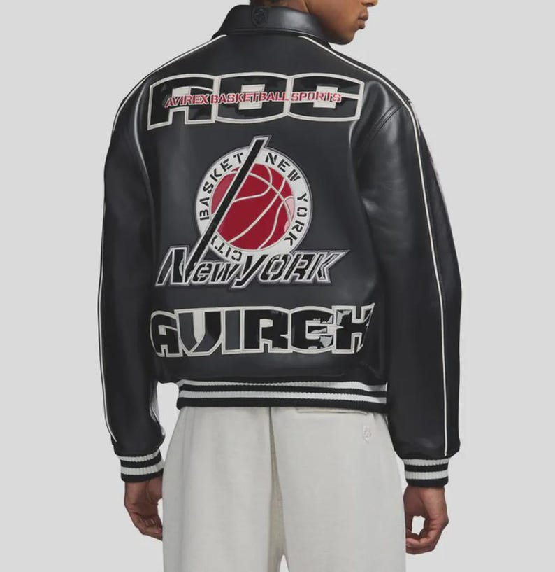 Puede incluir: Chaqueta de cuero negra con ribetes blancos y el texto "AVIREX BASKETBALL SPORTS" en los hombros. Un gr&aacute;fico de baloncesto con "New York" est&aacute; centrado en la espalda. La chaqueta tiene dobladillo y pu&ntilde;os acanalados.