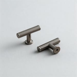 Puede incluir: Dos tiradores de armario en forma de T de níquel cepillado. Cada tirador tiene una barra cilíndrica con textura acanalada y un vástago corto unido a una base circular. Para cajones o armarios.