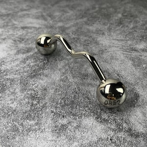 May include: A polished silver-toned curved barbell body jewelry piece featuring two spherical ends. The larger spherical end is engraved with the number 0452. The metal surface is highly reflective, showing light reflections across its smooth, undulating shape.
