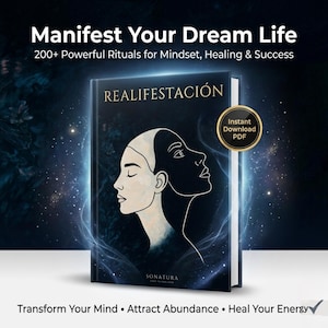 May include: A book titled "REALIFESTACIÓN" with the text "Manifest Your Dream Life" and "200+ Powerful Rituals for Mindset, Healing & Success." The cover features a woman's face split into light and dark halves. The book also has the text "Transform Your Mind • Attract Abundance • Heal Your Energy."