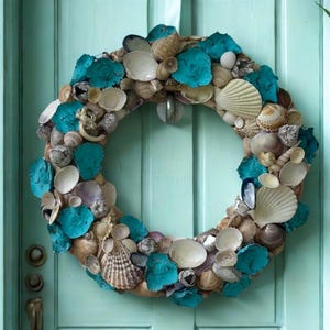 Peut inclure: Une couronne circulaire composée d'une variété de coquillages naturels et de fragments de coquillages teintés en bleu sarcelle. La couronne est suspendue par un ruban blanc et présente un arrangement dense de coquillages beiges, bruns et blancs.