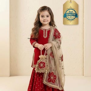 May include: A young girl in a red outfit with gold trim, holding a matching purse. The outfit includes a long-sleeved top and a skirt with white polka dots. A sheer scarf with floral embroidery completes the ensemble. A tag with "Best Quality Guaranteed" is visible.