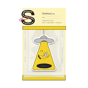 May include: A yellow fragrance card with a cartoon alien design. The alien is lying down in a yellow beam of light, with the word "bye" written above it. The card is labeled "shortcut LAB" and is designed for use in a car, wardrobe, or office.