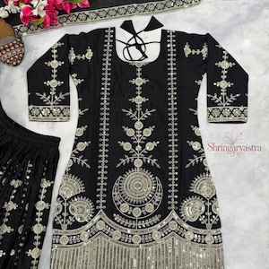 May include: Black embroidered tunic and matching pants set with silver embellishments. The tunic features intricate floral and geometric patterns, long sleeves, and a decorative neckline. The set includes a matching scarf and is suitable for special occasions.