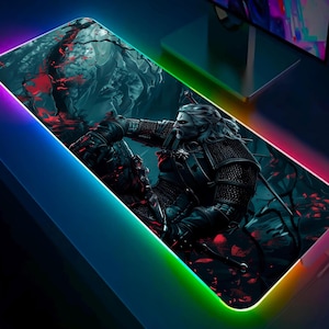 Può includere: Tappetino per mouse da gioco rettangolare con un'illustrazione dettagliata di un personaggio della serie The Witcher. L'opera raffigura un guerriero in armatura scura con lunghi capelli bianchi, su uno sfondo scuro e boscoso con accenti rossi. Il tappetino ha un bordo illuminato colorato.