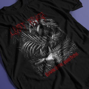 Può includere: Una t-shirt nera a maniche corte con un'illustrazione grafica bianca di una creatura scheletrica con denti e costole affilate. Il testo "LOST RIVER" appare in rosso in alto, e "GLOWING DEPTHS: HIDDEN TRUTHS" è stampato in rosso in basso.