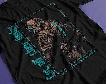 May include: A black short-sleeve t-shirt featuring a graphic of a futuristic armored figure in bronze tones. The design includes a teal rectangular border, the text "Cut off their limbs" in a distressed font, and "In space, there is only the scream inside your head."