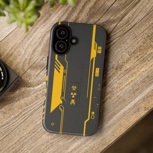 May include: A black phone case featuring yellow geometric patterns and hazard symbols. The case has a modern aesthetic with a biohazard symbol and industrial-style graphics. The case is designed to fit a smartphone.