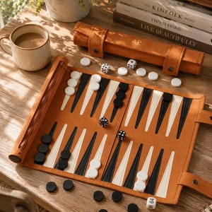 May include: A backgammon set with a tan leather case and board. The board is open, showing black and white game pieces and dice. A mug of coffee and decorative books are also visible.