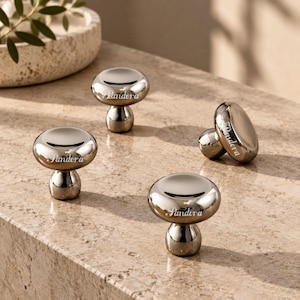 May include: Four mushroom-shaped cabinet knobs with a polished, reflective silver-tone metallic finish. Each knob features a rounded top and a smaller, cylindrical base. The word "Pandora" is engraved in a cursive script on the side of each knob.