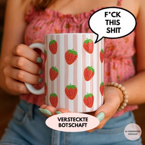 Könnte beinhalten: Ein weißer Keramikbecher mit einem wiederkehrenden Muster aus roten Erdbeeren und vertikalen hellrosa Streifen. Eine Sprechblase über dem Becher enthält den Text F*CK THIS SHIT. Unter dem Becher enthält eine ovale Form den Text VERSTECKTE BOTSCHAFT.