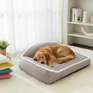 May include: A sleeping golden retriever rests on a gray dog bed with a white trim. The bed has a quilted center and a curved headrest with the text "DEEP SLEEP". The bed is on a white rug.