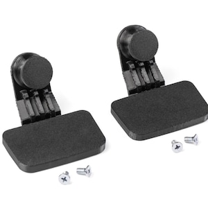 Peut inclure: Deux pieds de meubles en plastique noir avec des coussinets rectangulaires et des dessus ronds, ainsi que trois petites vis argentées, sont présentés sur fond blanc. Les pieds ont une conception articulée, probablement pour les meubles.