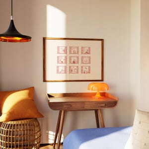 K&ouml;nnte beinhalten: Ein Holzschreibtisch mit einer Schublade und drei Beinen, gekr&ouml;nt von einer orangefarbenen Lampe. Ein gerahmter Druck mit neun Fensterillustrationen h&auml;ngt &uuml;ber dem Schreibtisch. Ein orangefarbenes Kissen liegt auf einem gewebten Hocker. Eine schwarze und goldene Pendelleuchte h&auml;ngt von der Decke.