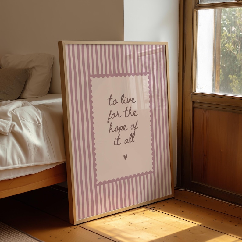 May include: A rectangular framed wall art print featuring a light pink background with vertical white stripes. In the center, a scalloped-edge rectangle contains the dark text 'to live for the hope of it all' and a small heart symbol below.