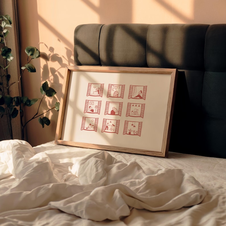 K&ouml;nnte beinhalten: Ein gerahmter Druck mit neun roten Illustrationen von Menschen in Fenstern. Das Kunstwerk hat einen cremefarbenen Hintergrund und einen hellen Holzrahmen. Der Druck wird auf einem Bett mit wei&szlig;er Bettw&auml;sche pr&auml;sentiert.