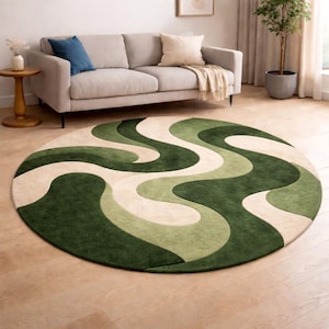 May include: A round rug with a retro design. The rug features a wavy pattern in shades of green and cream. The rug is placed on a wooden floor in front of a beige sofa with blue and cream pillows.