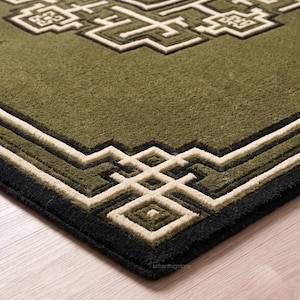 May include: A rectangular area rug featuring a deep olive green field with a thick black border and a raised, cream-colored geometric pattern. The design includes intricate, angular lines and square motifs that create a textured, layered appearance.