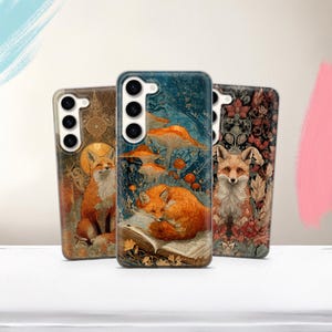 May include: Three phone cases with fox illustrations. The cases feature a variety of designs, including a fox sitting, a fox sleeping near mushrooms, and a fox surrounded by flowers. The cases have a glossy finish and are in shades of brown, orange, and blue.