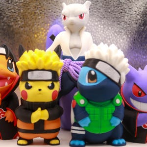 May include: A collection of five small plastic character figurines. The front row features an orange creature in a black cloak, a yellow creature with spiky hair and a headband, a blue creature in a green vest, and a purple creature in a black cloak.