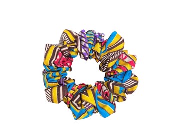 May include: A fabric hair scrunchie featuring a vibrant geometric pattern with bold stripes in shades of yellow, bright blue, magenta, and dark brown. The accessory has a gathered, ruffled texture and a circular shape with a central opening.