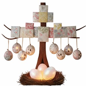 Puede incluir: Un árbol decorativo de Pascua con tronco y ramas marrones, adornado con cuadrados de tela estampada y adornos colgantes en forma de globo. La base presenta un nido con huevos brillantes y brillantes, creando una exhibición primaveral festiva.