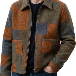 May include: A wool jacket with a patchwork design in shades of brown, orange, and gray. The jacket has a collared neckline, a full-length zipper, and two front pockets. The person is wearing blue jeans.