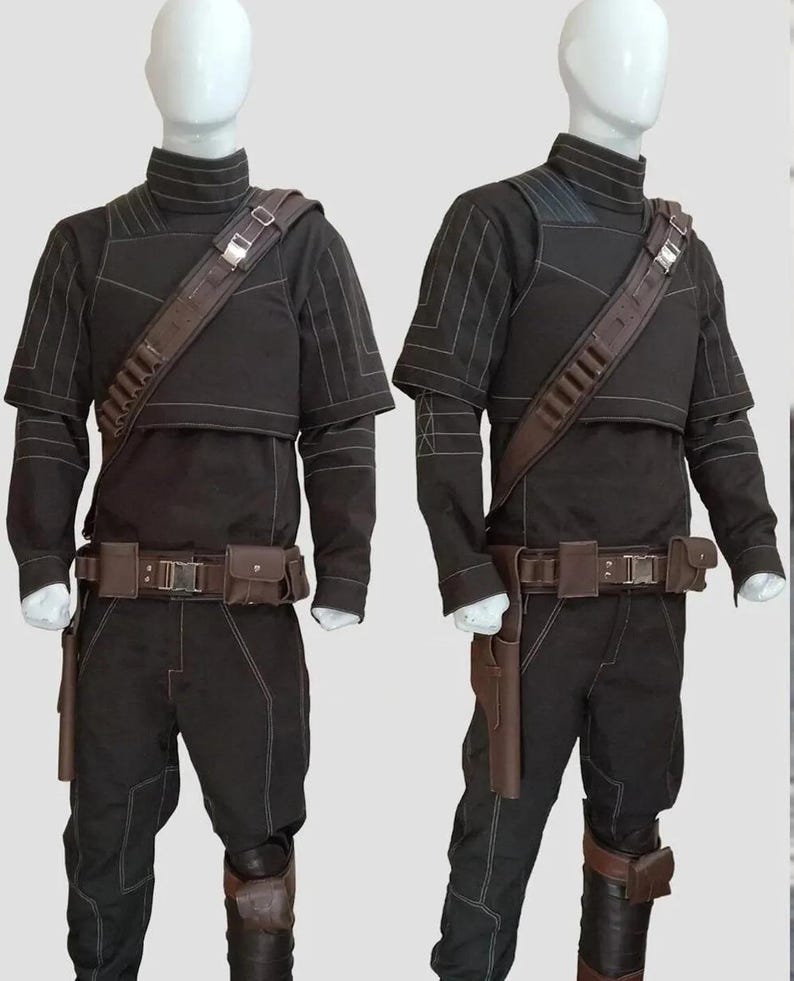 K&ouml;nnte beinhalten: Zwei schwarze Kost&uuml;me mit braunen Akzenten werden auf Schaufensterpuppen pr&auml;sentiert. Jedes Outfit umfasst ein Oberteil mit hohem Kragen, eine Hose, einen G&uuml;rtel mit Taschen und einen Schulterriemen. Die Kost&uuml;me haben wei&szlig;e N&auml;hte und braune Holster.