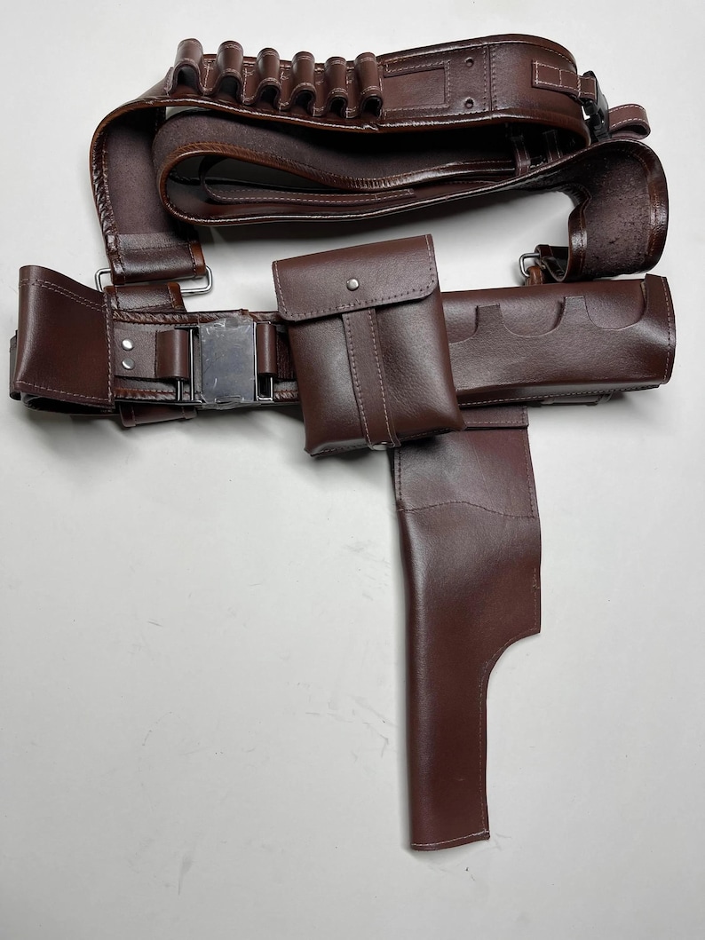 K&ouml;nnte beinhalten: Ein brauner Leder-Utility-G&uuml;rtel mit mehreren Taschen, einer Halterung und Schlaufen zur Aufnahme von Gegenst&auml;nden. Der G&uuml;rtel hat eine silberfarbene Schnalle und ist f&uuml;r das Tragen von Zubeh&ouml;r konzipiert.