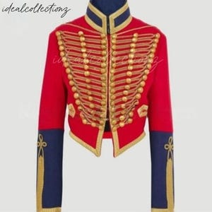 May include: A red military-style jacket with gold-colored embellishments and buttons. The jacket features navy blue accents on the collar and sleeves, with gold trim. The text "idealcollectionz" is visible in the upper left corner.